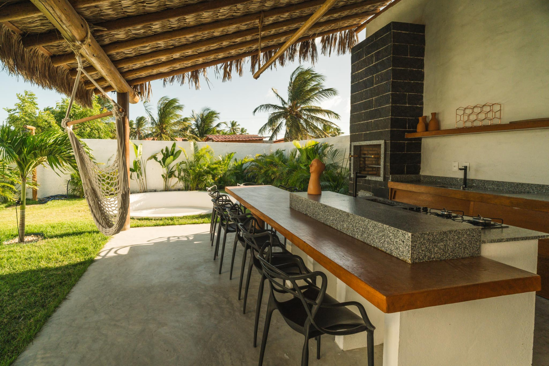 Espaço gourmet coberto com churrasqueira, ilha e mesa para refeições