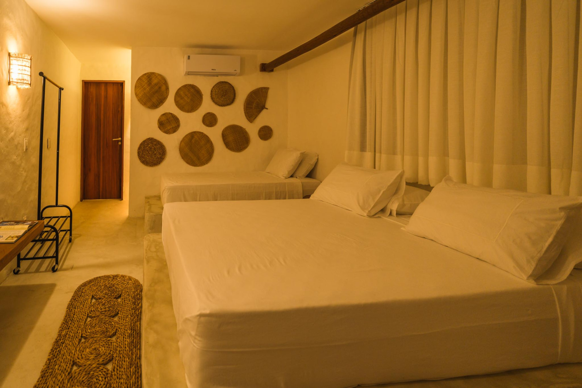 Suíte com cama de casal e cama auxiliar sob iluminação noturna