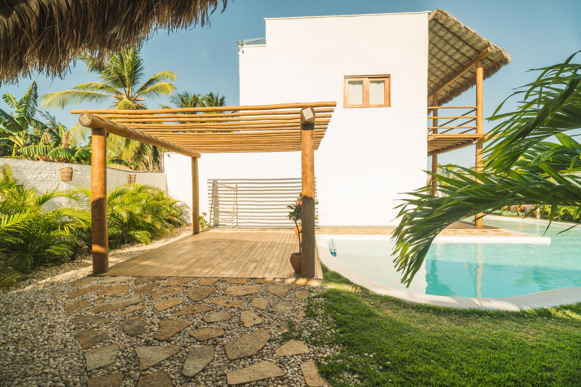 Fachada da casa, deck de madeira, jardim tropical e piscina