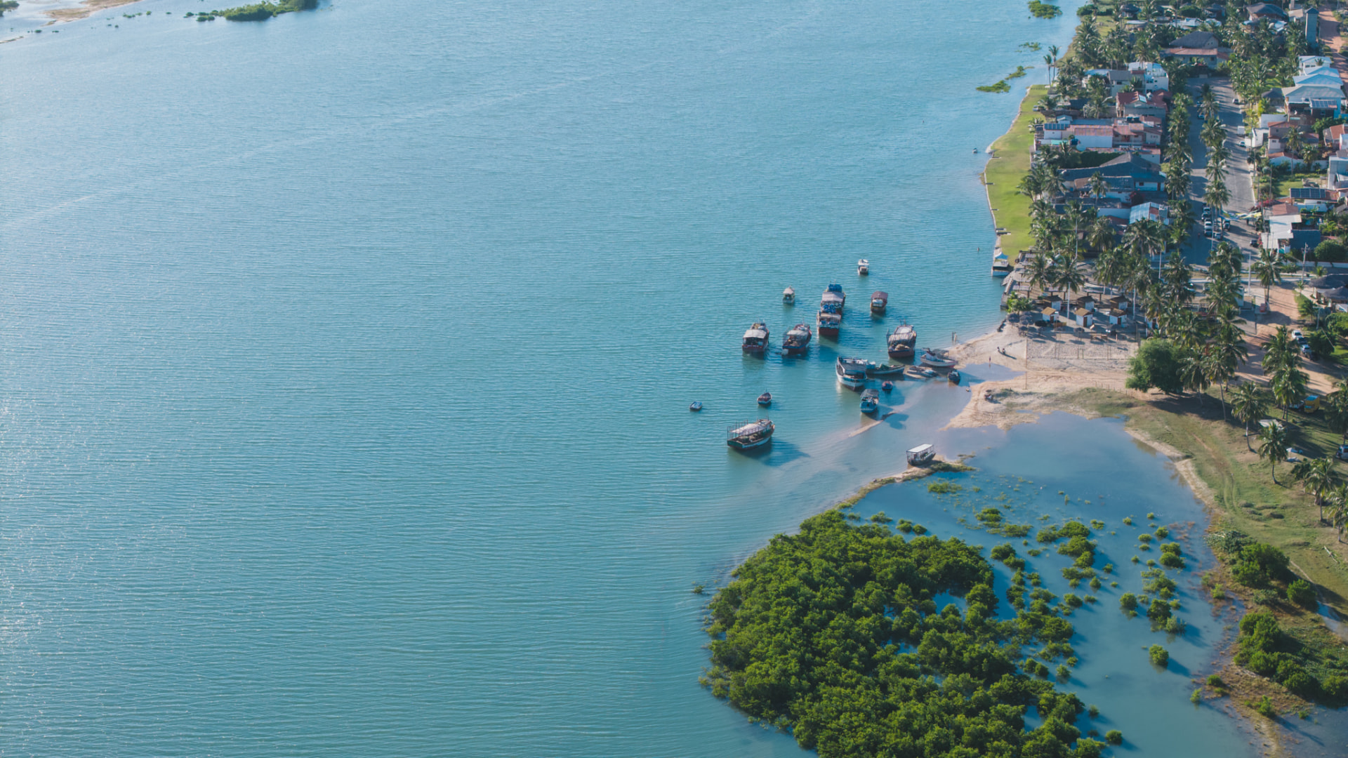 Vista aérea da lagoa da Ilha do Guajiru, com barcos, vila e vegetação costeira