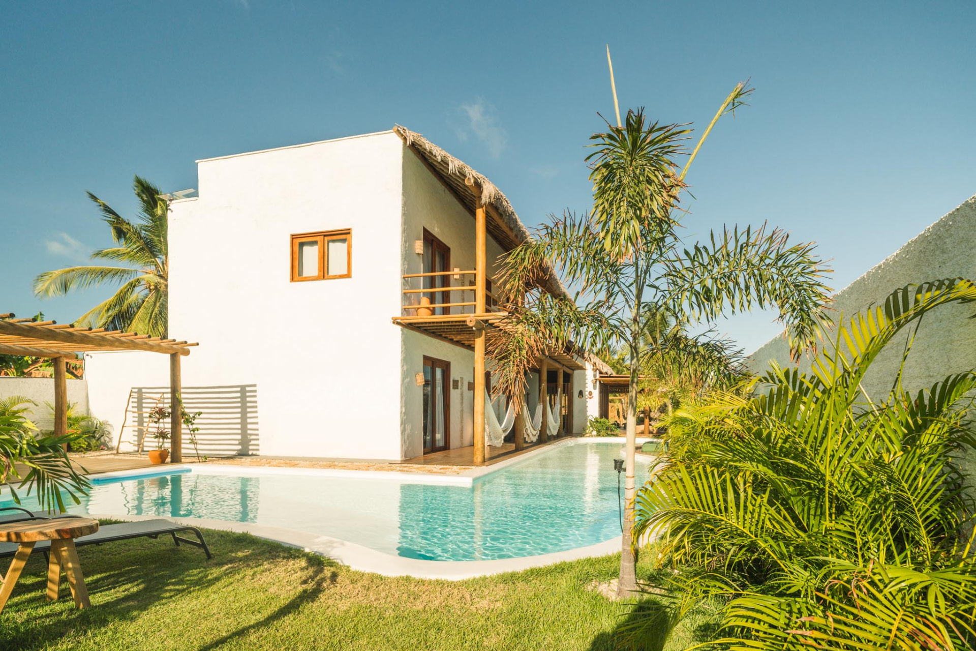 Fachada branca da Azulli Casa Boutique cercada pelo jardim e pela piscina