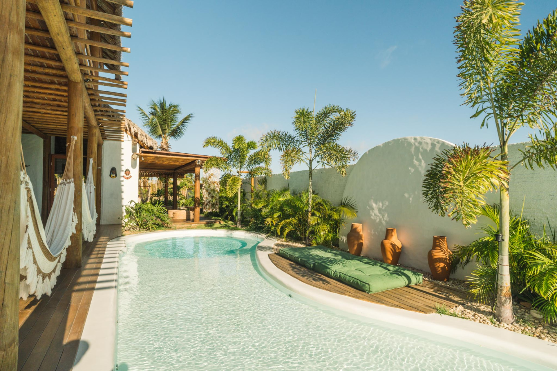 Piscina de formas orgânicas ao lado da varanda com redes