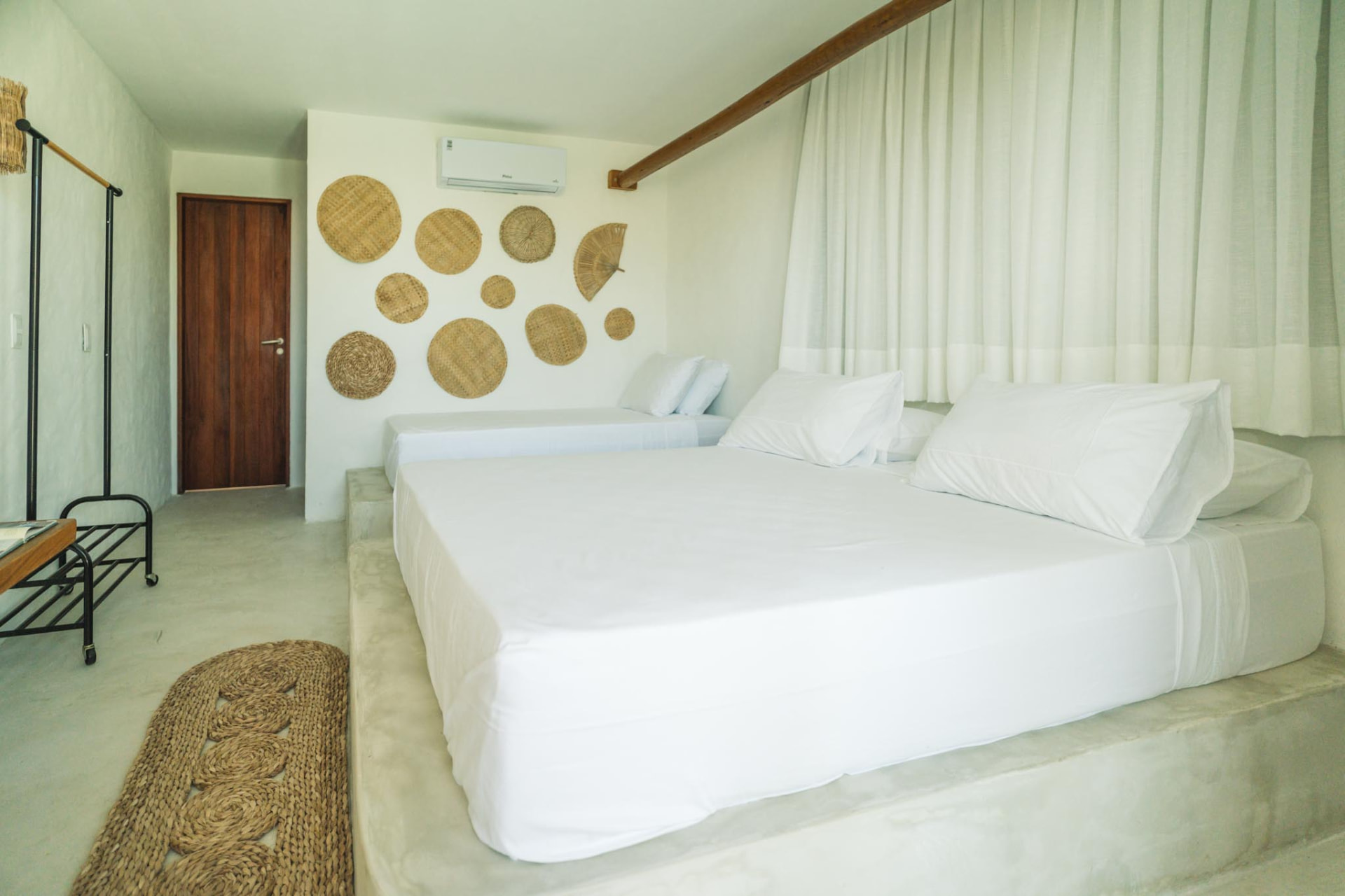 Suíte ampla com cama de casal, cama auxiliar e decoração em fibras naturais